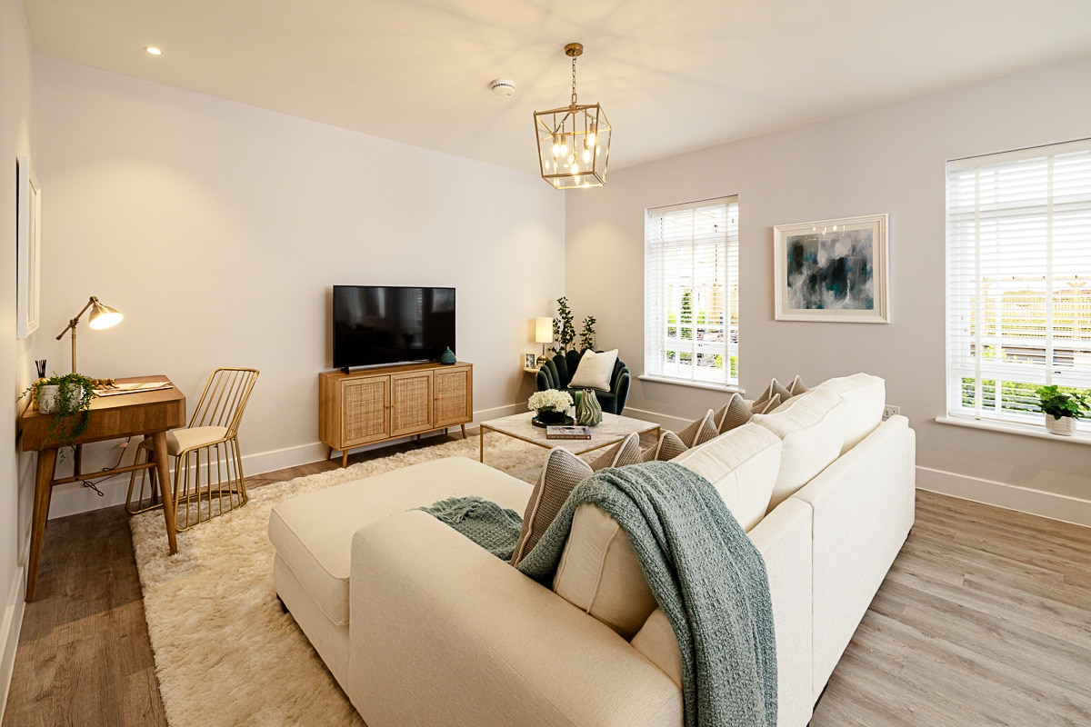 A living area at Terlingham Gardens showing a cream sofa facing a tv on a tv stand.