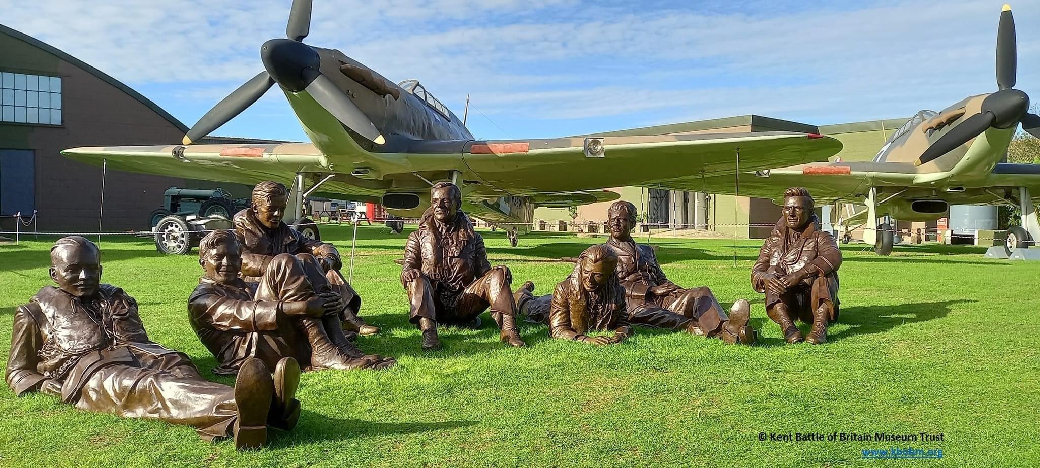 Statues of seven people Infront of old planes at the Battle Of Britain Museum in Hawkinge.