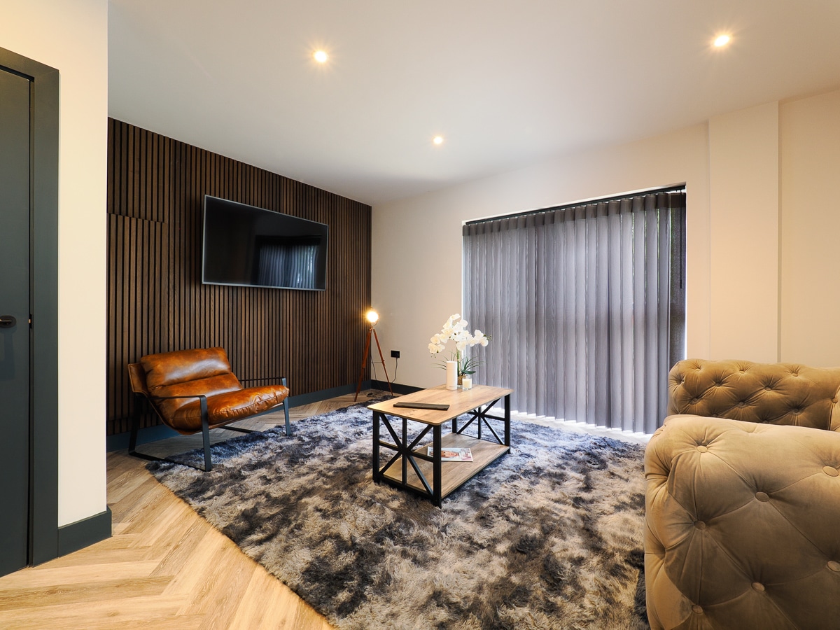 A lounge at a Hawker6 apartment with a chair, coffee table and large rug.