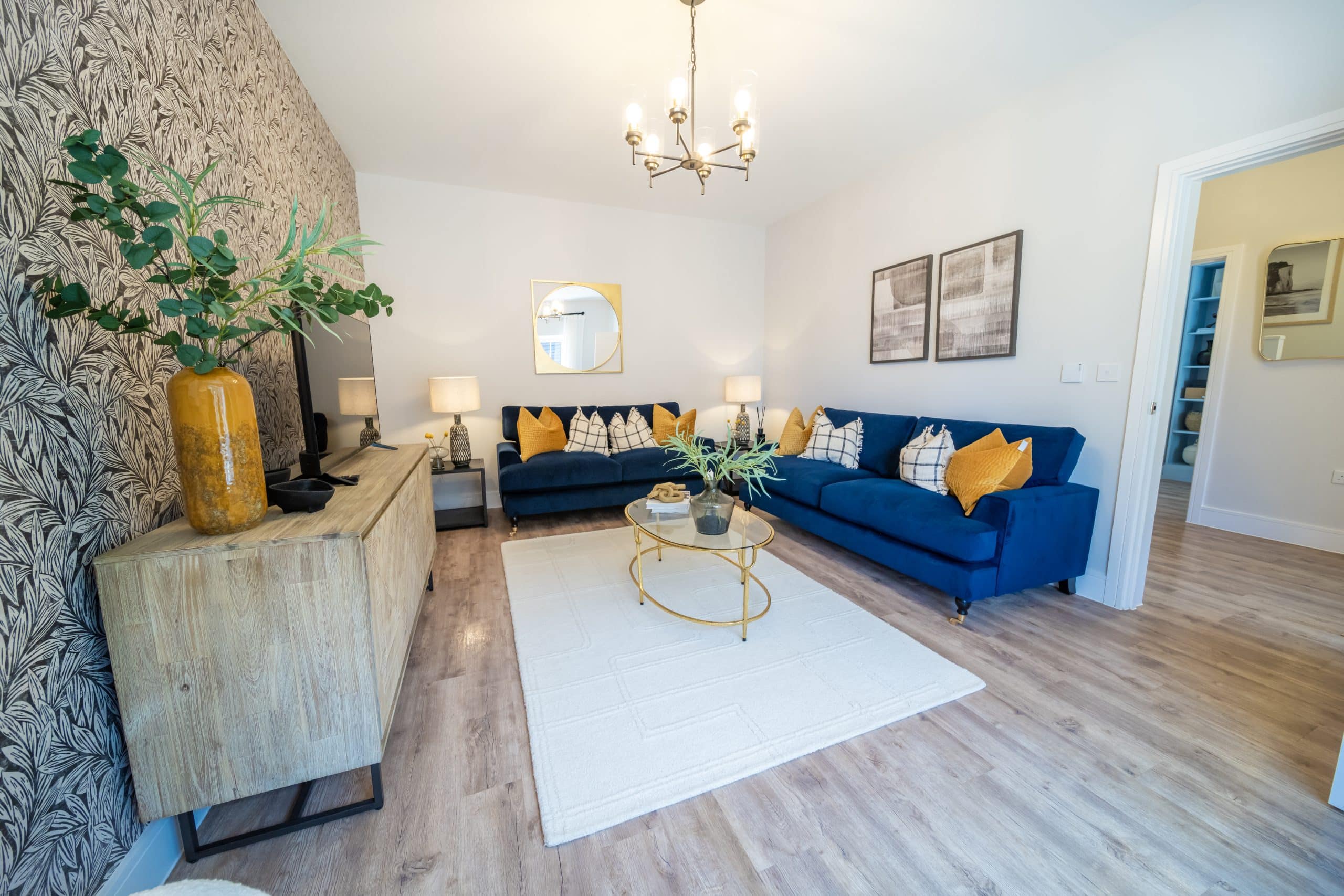 The lounge of a home at Poppy Fields with two blue sofas and a tv stand.