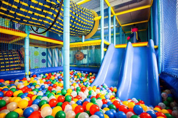 A child's indoor soft play, playground. Showing a ball pit with slides into it.